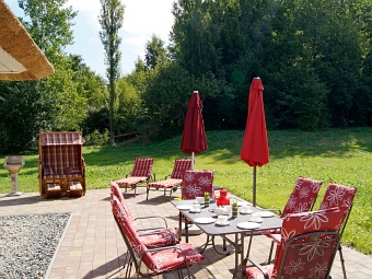 Die Süd-Terrasse mit Tisch, Gartenstühlen, Sonnenliegen, Grill und Strandkorb