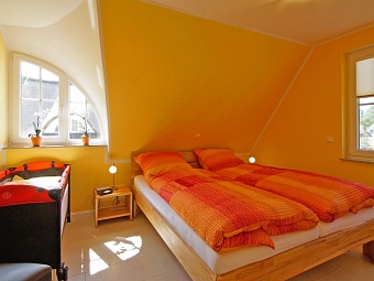 Ein Schlafzimmer mit Kinderreisebett im Dachgeschoss